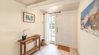 Entrance hall of 149 Salters Road with a wood console and orchid by the front door, Barbados
