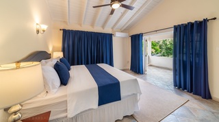 Master bedroom at 149 Salters Road with a king bed and navy curtains opening to a balcony, Barbados