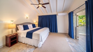 King bedroom under a beamed ceiling with doors to the garden at 149 Salters Road, luxury villa, Barbados