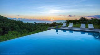 Atelier House infinity pool with sunset over the Caribbean ocean