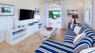 Cottage living area at Bananaquit with a blue and white striped sofa and wall TV, Barbados