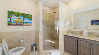 Corner rainfall shower and a yellow lifeguard hut painting in a Bella Vista en suite, Barbados