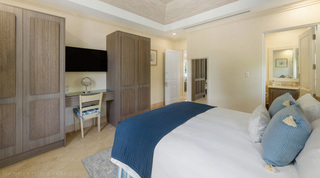 Fitted wardrobes and glass dressing table in a blue bedroom at Bella Vista, Barbados