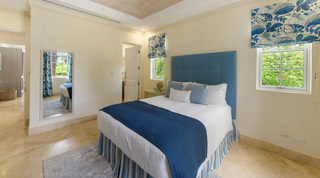 Double bedroom with a buttoned blue headboard and long mirror at Bella Vista, villa in Barbados