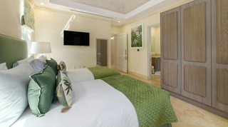 Green headboard and en suite doorway beyond the twin beds at Bella Vista villa, Barbados