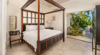 Mahogany four-poster bed and doors to a private garden terrace at Carlton Ridge villa, Barbados
