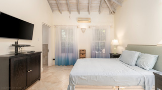 Pale blue linen, a dark media cabinet and an en-suite doorway at Carlton Ridge, Barbados