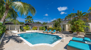 Pool and coral stone terrace framed by flowering hedges at Carlton Ridge, a luxury villa in St. James, Barbados