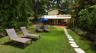 Sun loungers on the lawn and a stepping-stone path to the villa at Church Point 2, beachfront villa in Barbados
