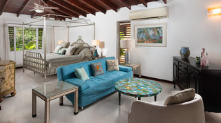 Master bedroom with a silver four-poster bed and teal sofa at Church Point 2, luxury villa in Barbados