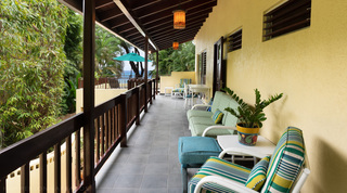 Upper covered verandah with cushioned seating and a sea glimpse at Church Point 2 villa, Barbados