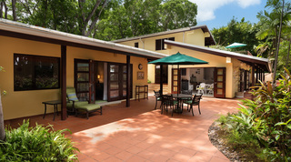 Terracotta-tiled courtyard with a green parasol over a dining table at Church Point 2, holiday villa in Barbados