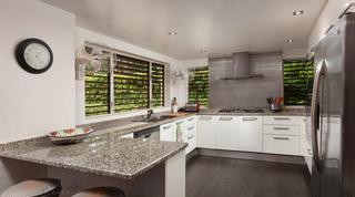 Kitchen with granite worktops, white units and louvred windows at Church Point 2, Barbados