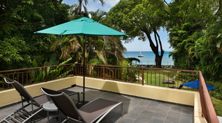 Sundeck with sun loungers and a teal parasol overlooking the sea at Church Point 2, Holetown, Barbados
