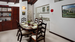 Cottage dining area with kitchenette and a set wooden table at Church Point 2, Holetown, Barbados
