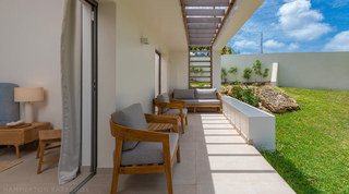 Covered bedroom veranda with teak armchairs beside a planted garden bed at Cloudbreak villa, Barbados