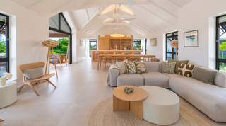 Sectional sofa facing the kitchen island beneath a vaulted truss ceiling at Cloudbreak villa in Barbados