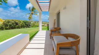 Round-backed teak armchairs on a bedroom veranda overlooking the countryside at Cloudbreak in Barbados