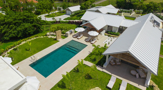 Aerial over Cloudbreak's pool, outdoor kitchen and covered terraces set among lawns and palms, Barbados