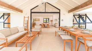 Cloudbreak's shaded terrace with a teak sofa and dining table opening into the open-plan living room, Barbados