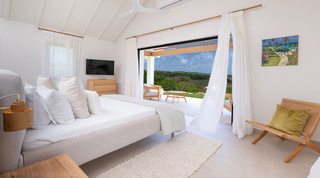 Cloudbreak's primary bedroom opening through voile curtains to a terrace and countryside beyond, Barbados