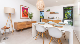 Cottage dining table set for six beneath a rattan pendant with a surf poster at Cloudbreak in Barbados