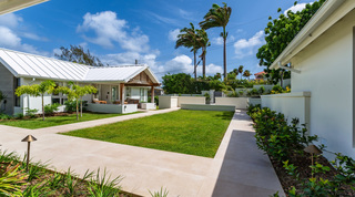 Landscaped courtyard with royal palms and a gabled porch at Cloudbreak, a St. James villa in Barbados