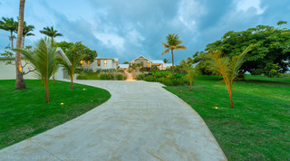 Curving driveway sweeping between lawns and young palms to Cloudbreak in the fading light, Westmoreland, Barbados