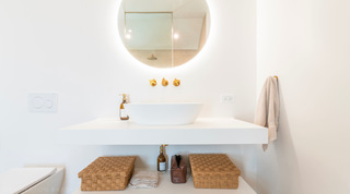 Backlit round mirror reflecting the walk-in rainfall shower above a vessel basin at Cloudbreak, Barbados