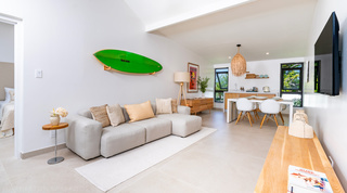 Guest cottage living room with a green surfboard, kitchenette and dining table at Cloudbreak villa, Barbados
