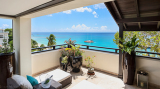 Potted plants on the terrace at Coral Cove 14 – Crowsnest in Barbados framing a red catamaran on the turquoise bay