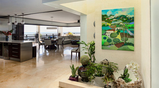 White orchid in an indoor planter at Coral Cove 14 – Crowsnest in Barbados, beneath a bright hillside painting