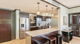Three wooden stools at the breakfast bar under glass pendants in the Coral Cove 14 – Crowsnest kitchen, Barbados