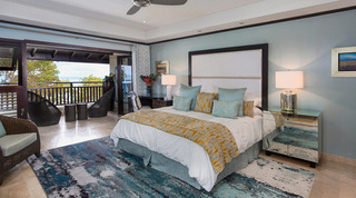 Tall upholstered headboard, mirrored chest and covered balcony beyond in a Coral Cove 14 – Crowsnest bedroom, Barbados