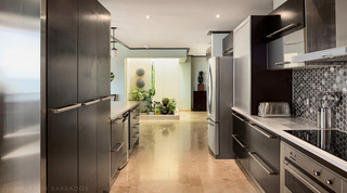 Galley kitchen at Coral Cove 14 – Crowsnest in Barbados, looking past the steel oven to a lit indoor planter