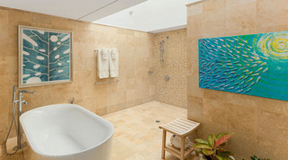 Freestanding bath and fish shoal painting in a stone-tiled en suite at Coral Cove 14 – Crowsnest, luxury apartment Barbados