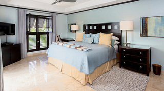 Cut-out headboard, pale blue coverlet and louvred shutters in a bedroom at Coral Cove 14 – Crowsnest in Barbados