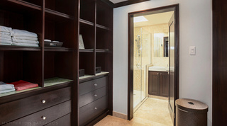Dark wood shelving, drawers and a lidded hamper in a dressing room beside an en suite at Coral Cove 14 – Crowsnest, Barbados