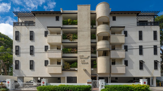 Street front with script Coral Cove nameplate and curved stair tower, Coral Cove 14 – Crowsnest penthouse in Barbados