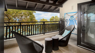 Treetop bedroom balcony at Coral Cove 14 – Crowsnest in Barbados, with wicker cocoon chairs and a blue monkey artwork