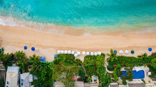 Top-down drone view over Paynes Bay by Coral Cove 14 – Crowsnest in Barbados, with surf, golden sand and white parasols