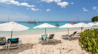 Green loungers and white parasols facing moored catamarans on Paynes Bay, Coral Cove 14 – Crowsnest beach apartment, Barbados