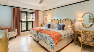 Cane headboards, blue chrysanthemum duvets and orange floral throws in the Coral Cove 14 – Crowsnest twin bedroom, Barbados