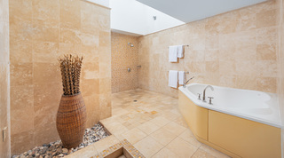 En-suite bathroom with panelled corner bath and walk-in travertine shower at Coral Cove 15 - Penthouse, Barbados
