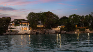 Grotto arches and headland buildings glowing at dusk across the water, Crystal Springs, Barbados
