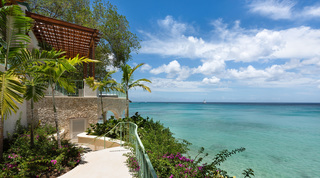 Railed clifftop path past a coral stone wall above turquoise water, Crystal Springs, The Garden, Barbados