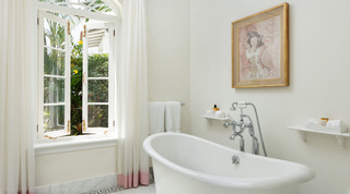 Freestanding slipper bath below a gilt-framed portrait and open casement window, Crystal Springs, Barbados
