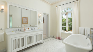 Bathroom with a roll-top bath below an arched garden window at Crystal Springs villa, St. James, Barbados