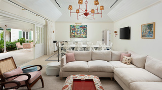 Open-plan lounge at Crystal Springs, a red chandelier in woven shades above sofas, meeting room beyond, Barbados