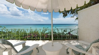 Green-edged parasol shading white wooden chairs above the turquoise sea, Crystal Springs, Barbados